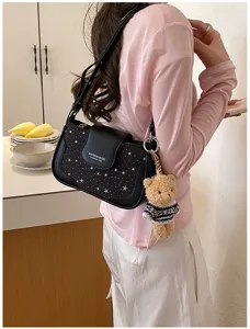 Vue détaillée du sac à épaule noir à motif d'étoiles pour femmes avec pendentif ours en peluche.