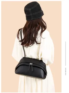 Minimalist black leather shoulder bag for women, retro underarm bag with zipper and tassels.