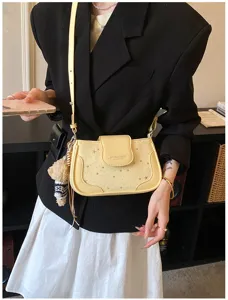 Vue détaillée du sac à bandoulière en cuir jaune avec étoiles et charmant pendentif.