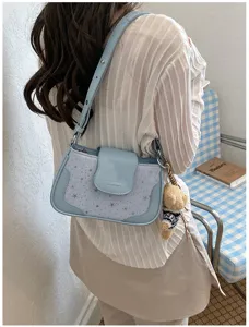 Vue détaillée du sac porté épaule bleu clair avec motif étoiles et joli pendentif.
