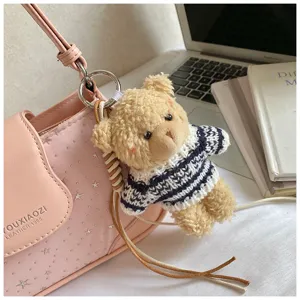 Gros plan du sac porté épaule en cuir rose avec joli pendentif ours en peluche.