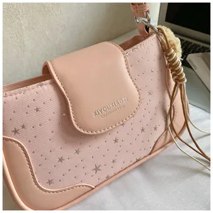 Sac à épaule rose avec motif étoilé, fermeture à rabat élégante et pendentif à pampilles chic.