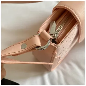 Détail de sac bandoulière rose motif étoiles, fermeture éclair et quincaillerie.