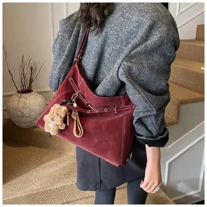 Vintage maroon slouchy shoulder tote bag detail showcasing soft leather texture and cute bear charm.