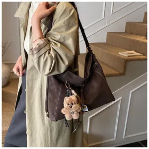 Detail shot of the vintage brown hobo shoulder bag with contrast stitching and charm.