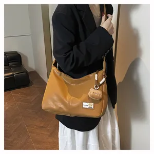 Brown slouchy hobo shoulder bag detail featuring soft leather texture and cute bear pendant.