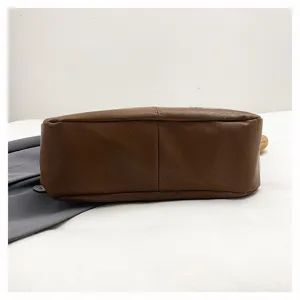 Brown soft leather dumpling bag bottom detail view, minimalist commuter fashion accessory.