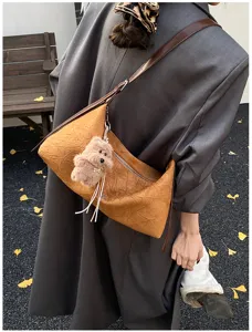 Detail view of the retro crinkled brown shoulder bag with cute plush bear pendant.