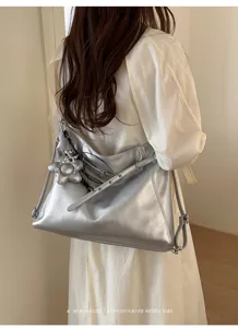 Vista ravvicinata e dettagliata di elegante borsa argentata metallizzata con ciondolo floreale.