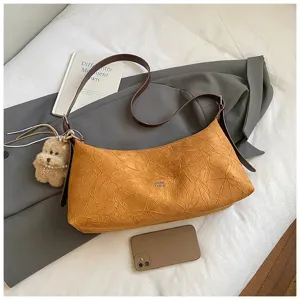 Detailed view of trendy pleated baguette shoulder bag with cute dog pendant and textured fabric.