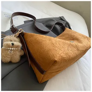 Detailed view of the vintage wrinkled baguette shoulder bag with cute fluffy bear plush charm.
