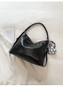 Vista dettagliata di una borsa a spalla nera in pelle PU con elegante ciondolo floreale argentato.