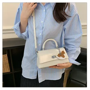 Chique witte lederen schoudertas met schattig schommelpaard bedeltje, trendy mini handtas.