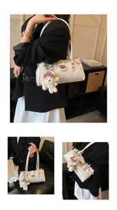 Detailed view of white shoulder bag with cute bear charm and metal turn-lock clasp.