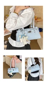 Stylish blue patent leather shoulder bag with chic rivets and a cute white bear pendant.