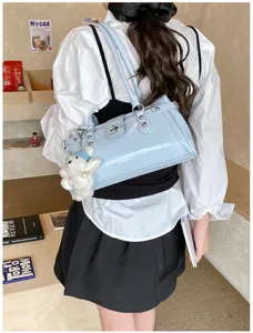 Detailed view of the stylish light blue patent leather shoulder bag with chic rivets and cute bear pendant.