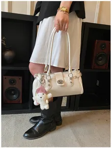 White stylish shoulder bag for women with chic rivets, minimalist design and cute bear charm.