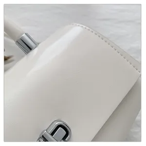 Gedetailleerd uitzicht op een chique witte PU-lederen handtas met elegant zilveren metalen slot.