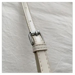 Detail van de verstelbare gesp van de witte kunstledzen handtasschouderriem voor dames tas