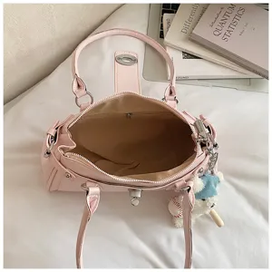 Pink leather handbag detail view, stylish commuter shoulder bag with metal lock and cute charm.