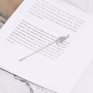 Closeup detail of a vintage silver leaf brooch lapel pin placed on an open book page.