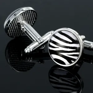 Silver tone metal round cufflinks featuring black and white zebra pattern glass cabochon details.