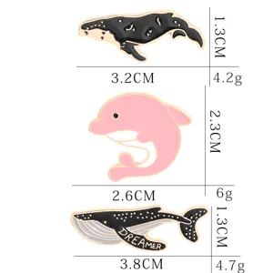 Detail view of cute ocean animal metal enamel pins including whale and pink dolphin with size specs.