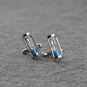 Detailed shot of silver-tone hourglass cufflinks with blue sand, classy shirt accessories.