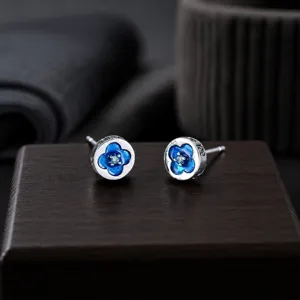 Vue détaillée des boucles d'oreilles clous argentées à fleurs bleues et design unique.