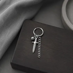 Gros plan détaillé de boucle d'oreille créole argentée punk gothique avec pendentif poignard.