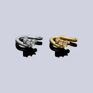 Vista dettagliata di eleganti orecchini cuff argentati e dorati con zirconi lucidi.