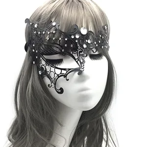 Detalle de máscara de metal negro, diseño calado de filigrana intrincada con pedrería brillante.