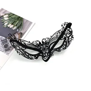 Close-up detail of black metal filigree masquerade mask with intricate cutout patterns.