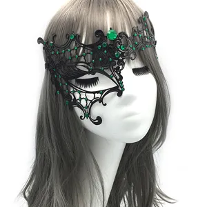 Vista detallada de máscara de metal negro con diamantes de imitación verdes para fiestas.