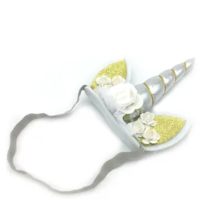 Details of unicorn horn headband with glitter ears and white flowers for kids party.
