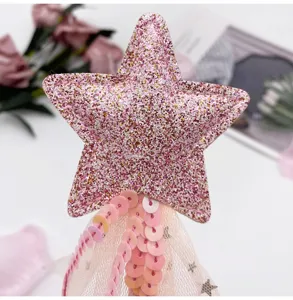 Gros plan d'une baguette magique étoile scintillante rose avec résille et détails pailletés.