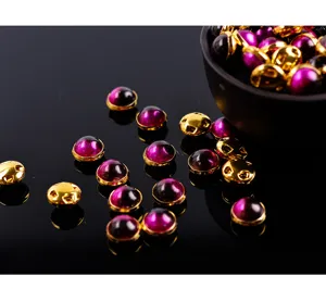 Nahaufnahme von violetten Cabochon-Knöpfen mit Goldrand, ideal für Nageldesign und Basteln.