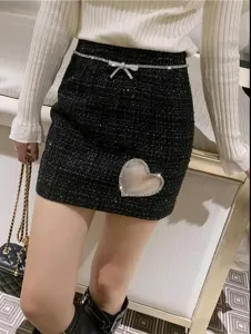 Nahaufnahme der schwarzen Tweed-Minirock mit Strass-Schleifengürtel und Herz-Ausschnitt.