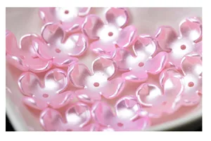Detailaufnahme von rosa perlmuttenen vierblättrigen Blumenperlen für Bastelarbeiten und DIY-Schmuck.
