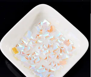 Nahaufnahme rechteckiger Aurora Nagel-Strasssteine in weißer Schale, schimmernde Kristalldetails.