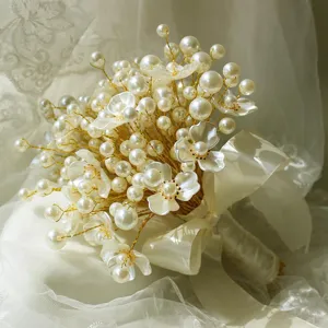 Detalle de ramo de flores de perlas hecho a mano, alambre dorado cuentas blancas novia.