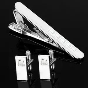 Silver metal tie clip and cufflinks set with square clear crystals, detailed close-up.