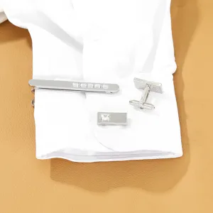 Close-up detail of silver alloy tie clip and cufflink set with square rhinestone decor.