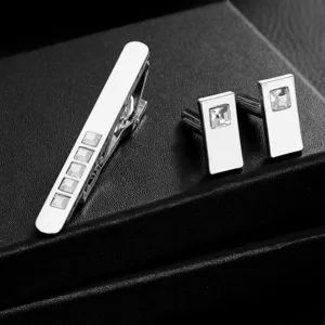 Silver men tie clip and cufflinks set close-up, square crystal inlaid business suit accessory detail.