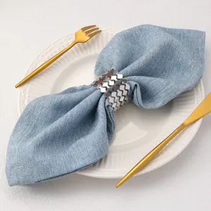 Elegante portatovaglioli in metallo ondulato con tovagliolo in tessuto blu per decorazione.