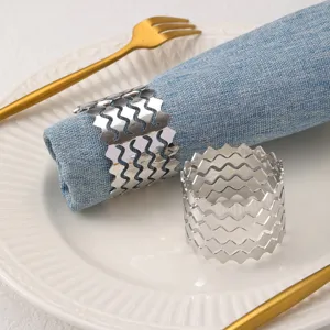 Dettaglio dell'anello portatovagliolo in metallo argentato ondulato con design a zig-zag unico.