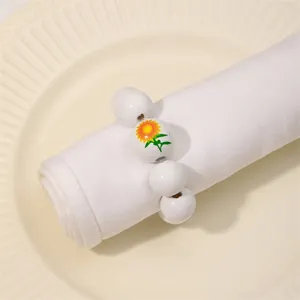 Primer plano del servilletero de cuentas de madera blancas con diseño de girasol detallado.