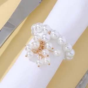 Close-up detail of the elegant white faux pearl napkin ring with gold chain charms on table.