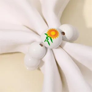Detalle de primer plano de servilletero de cuentas de madera blanca con motivo de girasol.