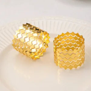 Anelli portatovaglioli in metallo dorato con design ondulato elegante per la tavola.